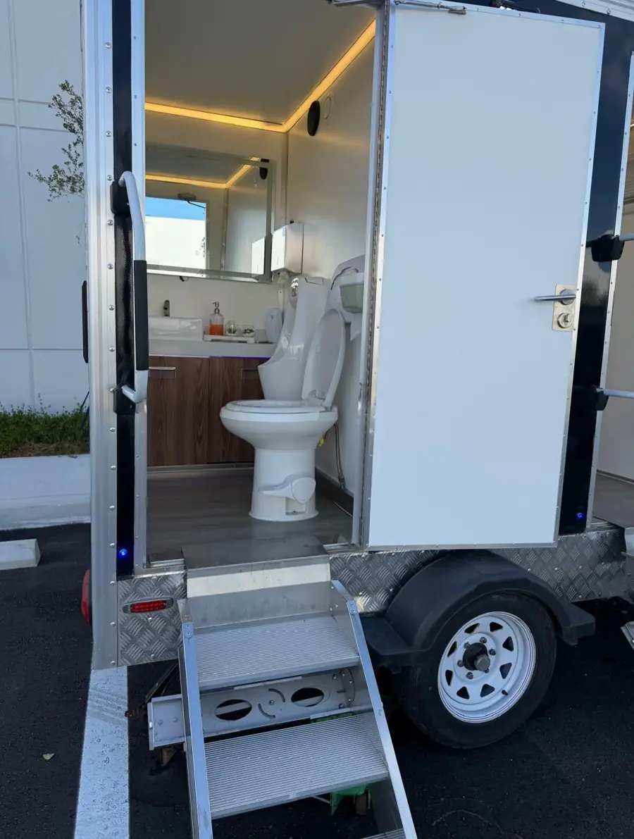 Inside a restroom trailer stall with a toilet, vanity and lights